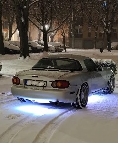 The silver MX-5 in the snow with purple underglow
